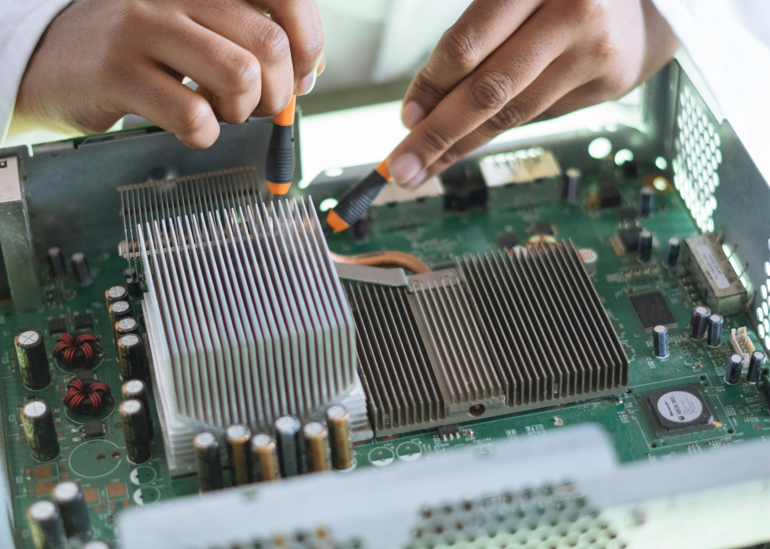 Close-up of a technician repairing a computer motherboard, focusing on microprocessor and heat sink.