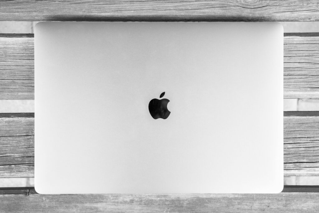 Black and white photo of a closed laptop on a rustic wooden table. Minimal and classic design.